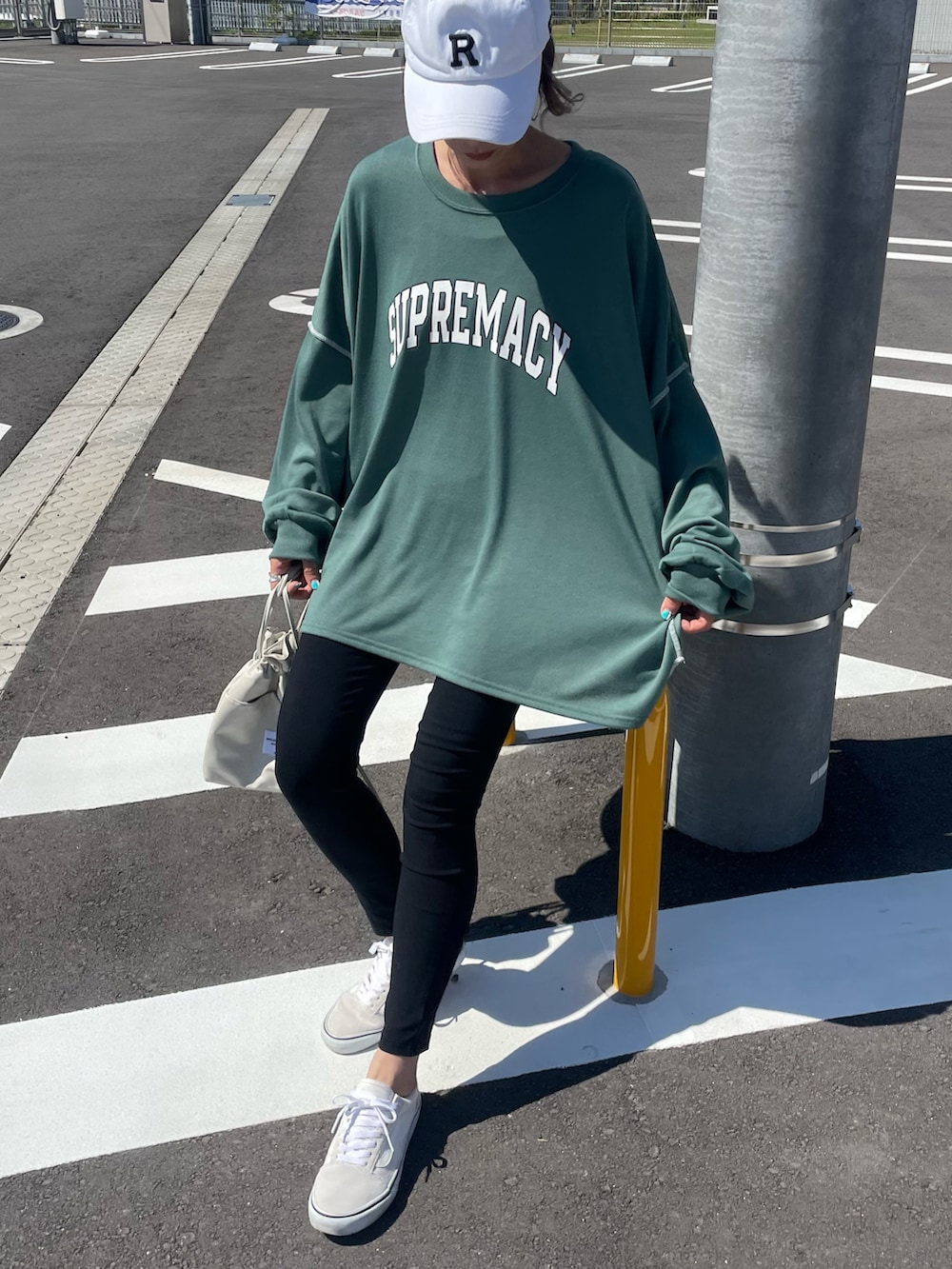 グリーン系のスウェット、ブラック系のその他パンツ、ホワイト系のショルダーバッグを着用したレディースの春コーディネートの2枚目の写真