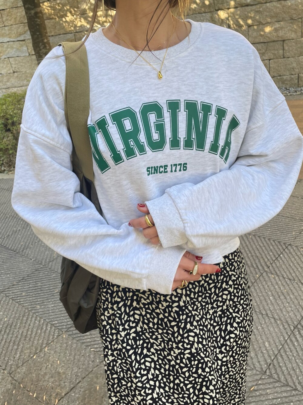 グリーン系のスウェット、ブラック系のスカート、ホワイト系のスニーカーを着用したレディースの冬コーディネートの5枚目の写真