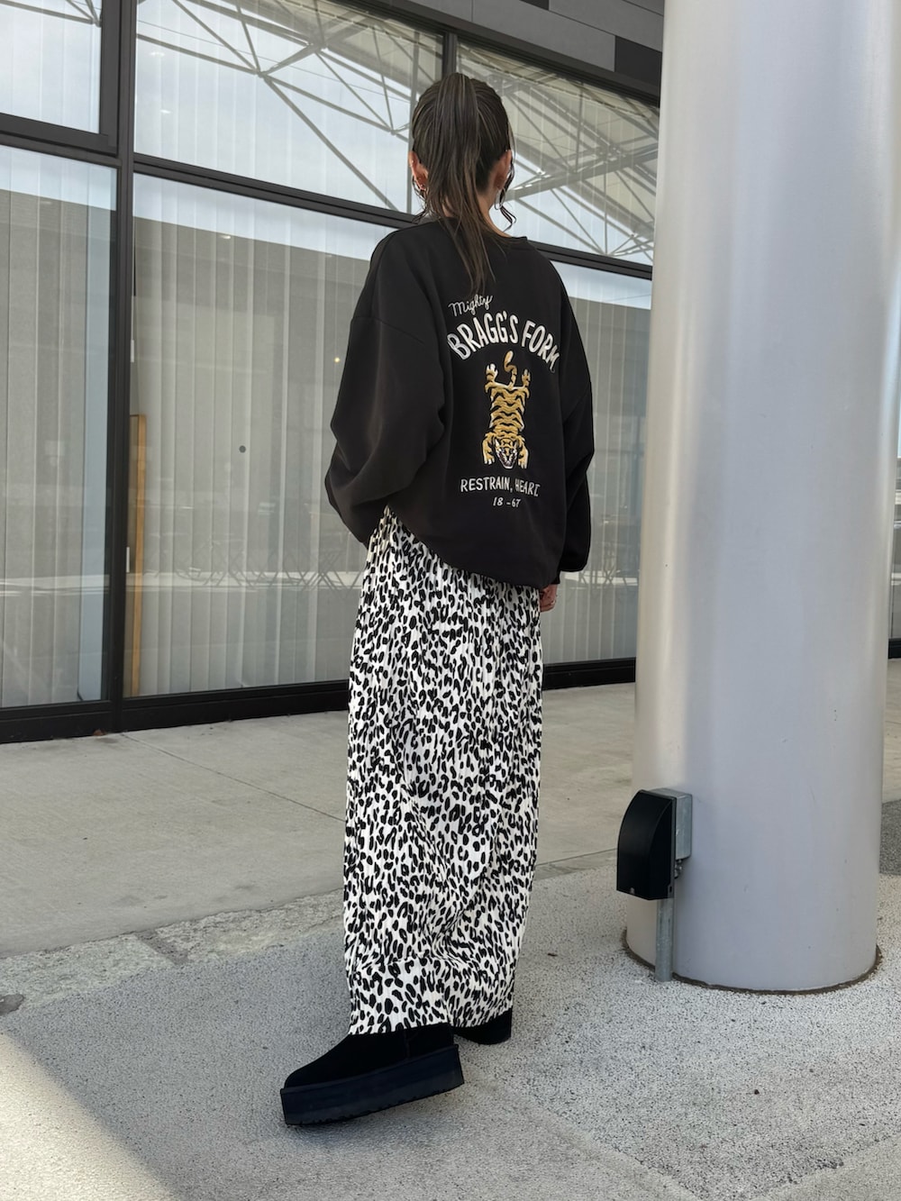 ブラック系のスウェット、ホワイト系のスカート、ブラック系のブーツを着用したレディースの秋コーディネートの3枚目の写真