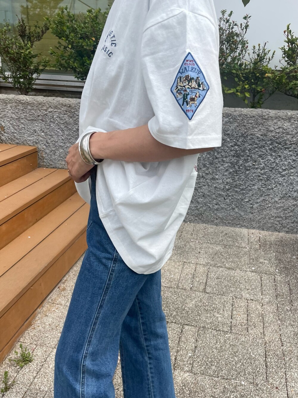 ホワイト系のTシャツ/カットソー、ブルー系のデニムパンツ、ブラック系のサンダルを着用したレディースの春コーディネートの3枚目の写真