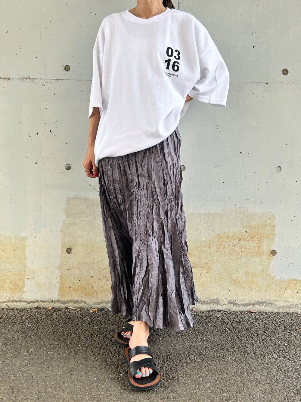 ホワイト系のTシャツ/カットソー、グレー系のスカート、ブラック系のサンダルを着用したレディースの夏コーディネートの2枚目の写真