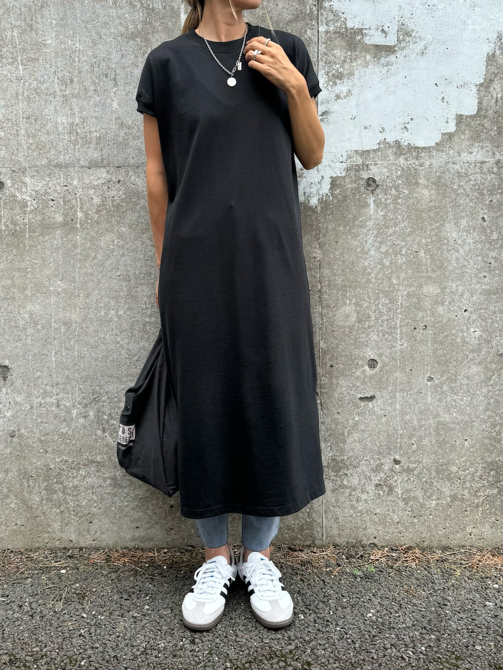 ブラック系のワンピース、ブルー系のデニムパンツ、ホワイト系のスニーカーを着用したレディースの夏コーディネートの2枚目の写真