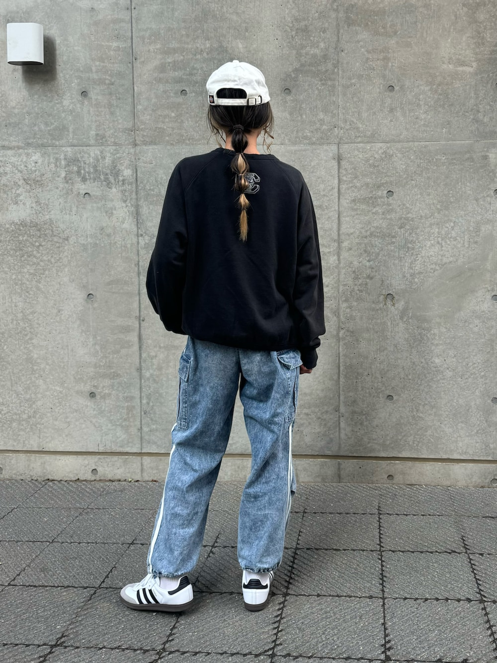 ブラック系のスウェット、ブルー系のデニムパンツ、ホワイト系のスニーカーを着用したレディースの冬コーディネートの3枚目の写真