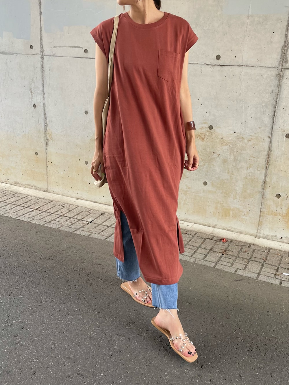 オレンジ系のワンピース、ベージュ系のトートバッグ、ブルー系のデニムパンツを着用したレディースの夏コーディネートの5枚目の写真