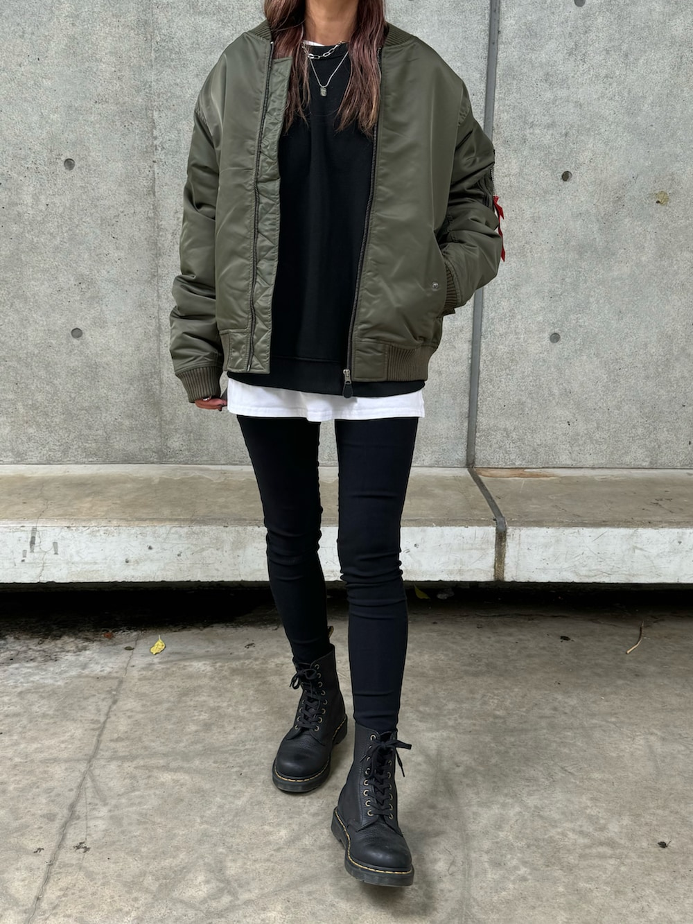 グリーン系のミリタリージャケット、ブラック系のスウェット、ホワイト系のその他パンツを着用したレディースの秋コーディネートの2枚目の写真