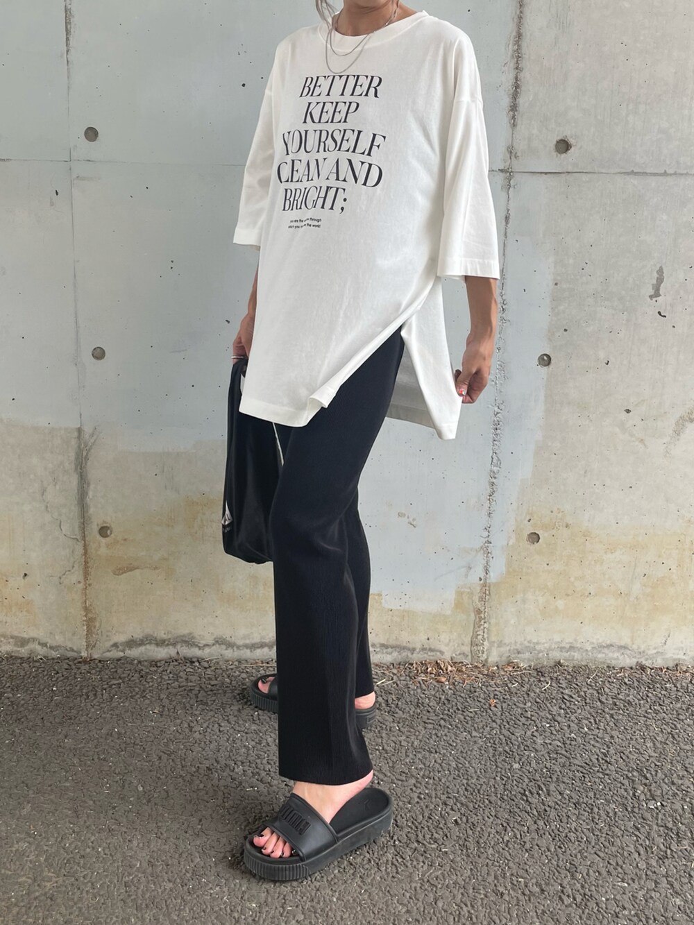 ホワイト系のTシャツ/カットソー、ブラック系のサンダル、その他のエコバッグ/サブバッグを着用したレディースの夏コーディネートの2枚目の写真