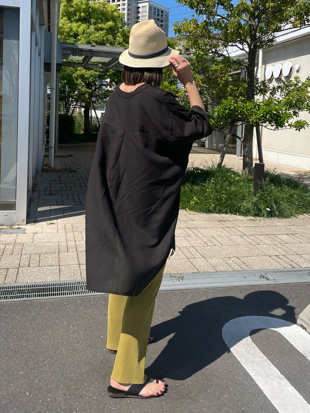 ブラック系のシャツ/ブラウス、ブラウン系のサンダル、ベージュ系のハットを着用したレディースの春コーディネートの2枚目の写真