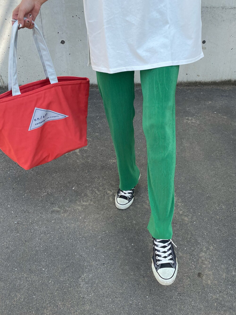 グリーン系のTシャツ/カットソー、オレンジ系のトートバッグ、ブラック系のスニーカーを着用したレディースの春コーディネートの5枚目の写真