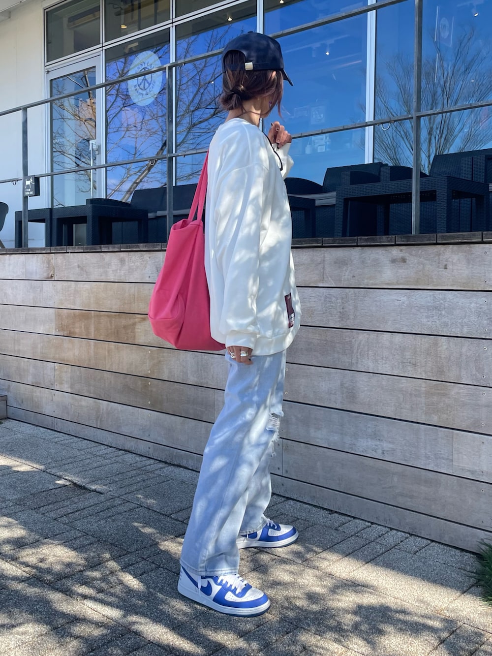 ホワイト系のスウェット、ブルー系のデニムパンツ、ピンク系のトートバッグを着用したレディースの春コーディネートの3枚目の写真