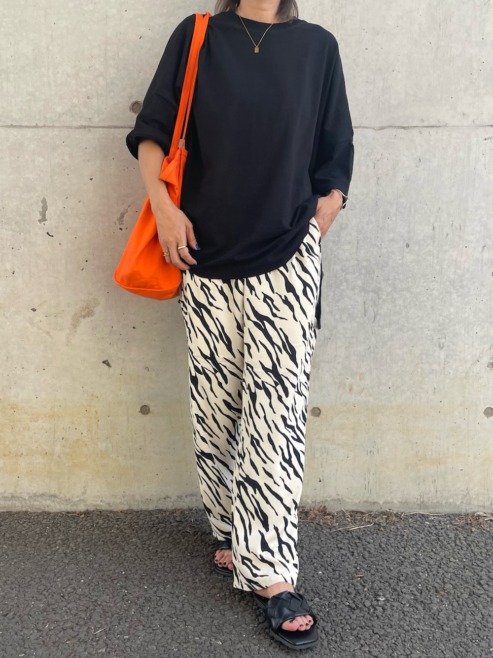 ブラック系のTシャツ/カットソー、ホワイト系のその他パンツ、オレンジ系のトートバッグを着用したレディースの春コーディネートの3枚目の写真