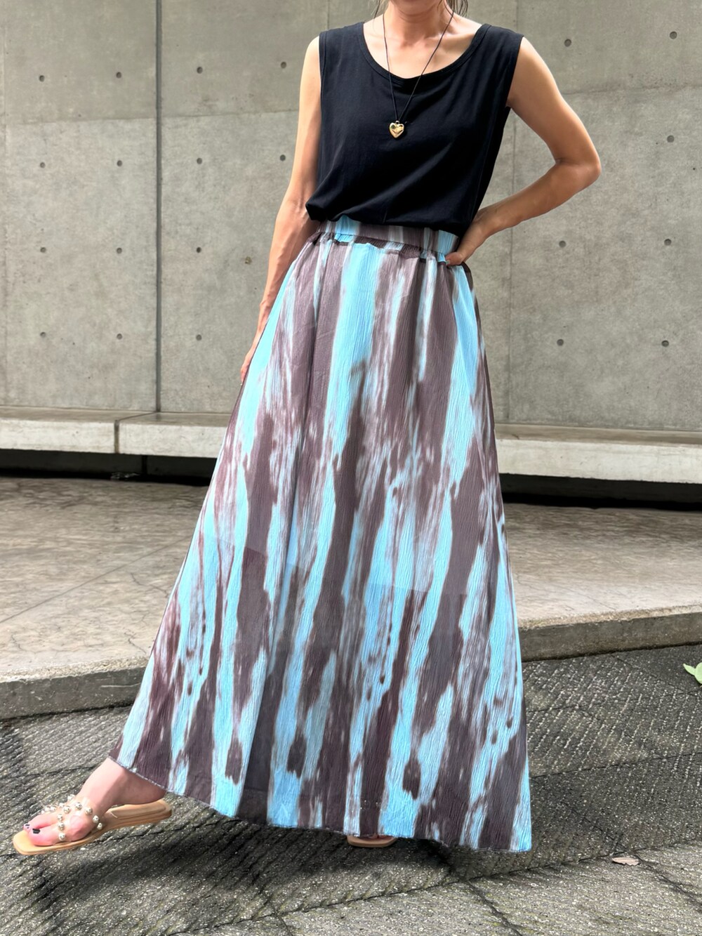 ブラック系のタンクトップ、ブルー系のスカート、ベージュ系のサンダルを着用したレディースの夏コーディネートの3枚目の写真