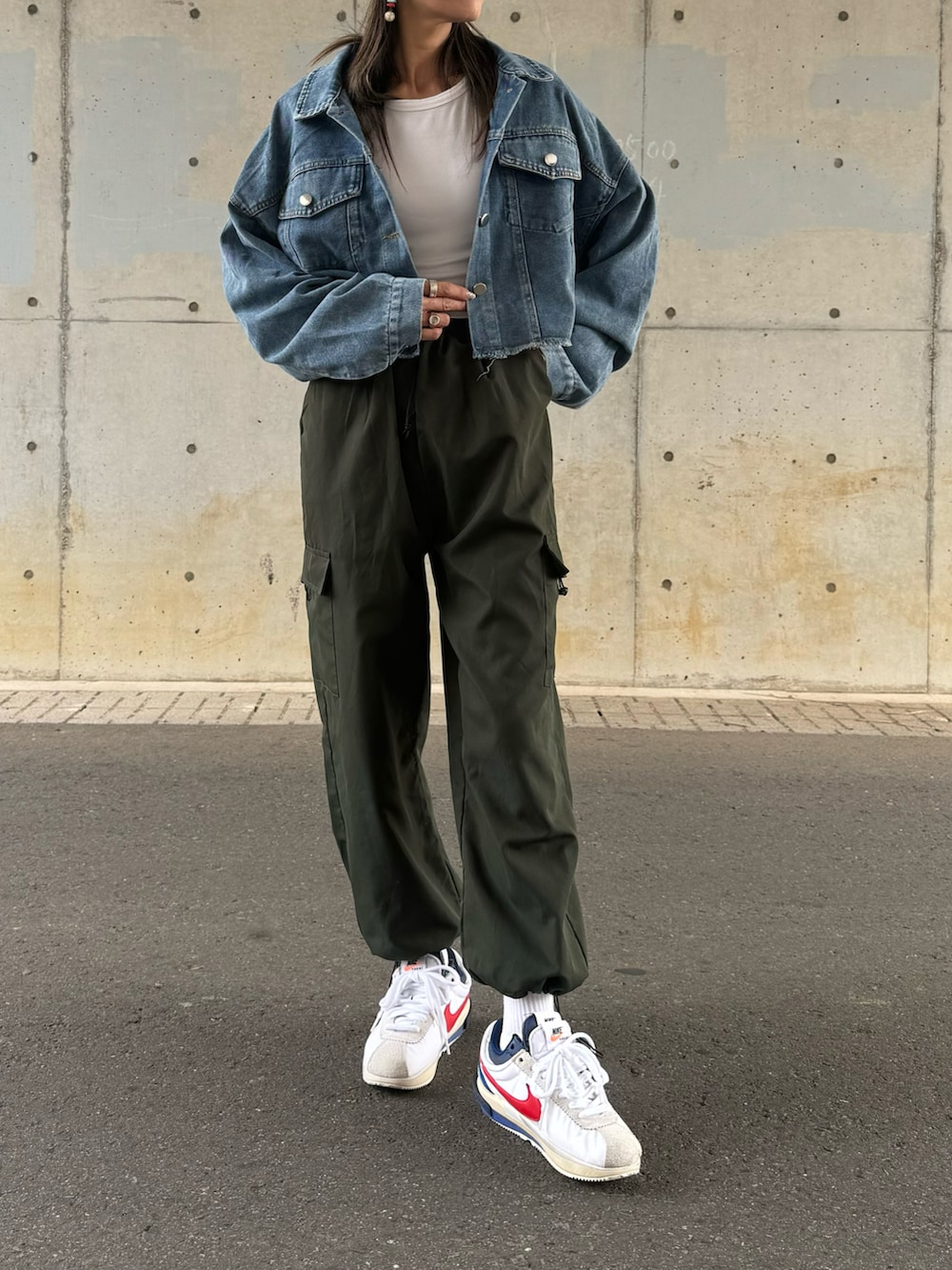 ブルー系のデニムジャケット、グリーン系のカーゴパンツ、ホワイト系のスニーカーを着用したレディースの春コーディネートの2枚目の写真