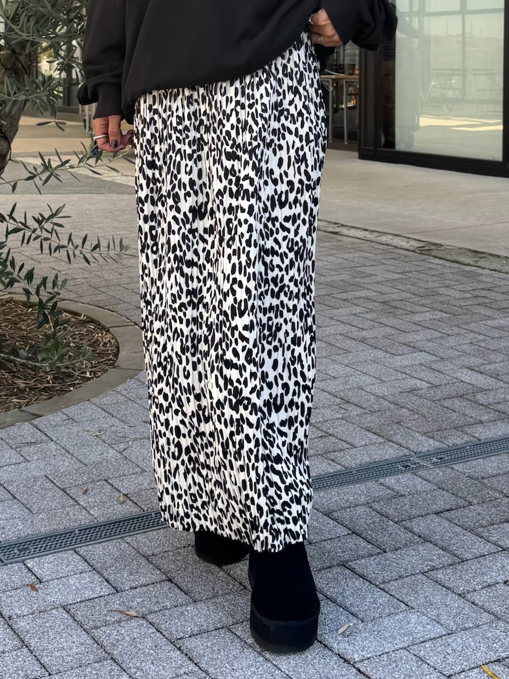 ブラック系のスウェット、ホワイト系のスカート、ブラック系のブーツを着用したレディースの秋コーディネートの4枚目の写真