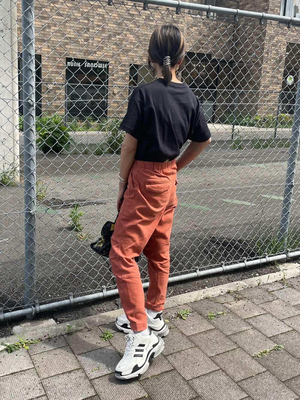 ブラック系のTシャツ/カットソー、レッド系のその他パンツ、ブラック系のバッグを着用したレディースの春コーディネートの2枚目の写真