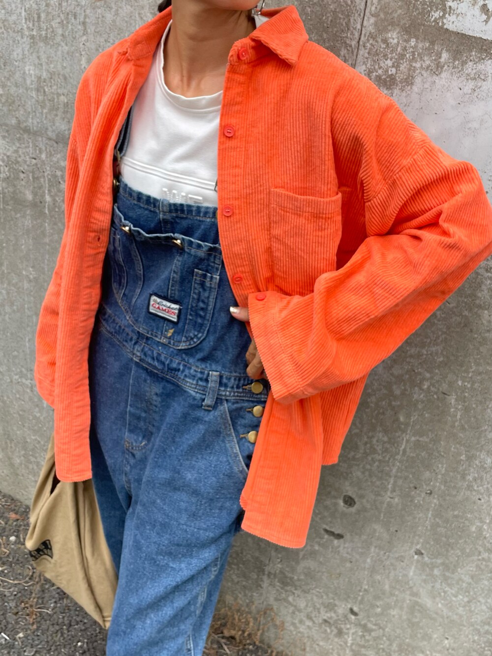 オレンジ系のシャツ/ブラウス、ホワイト系のTシャツ/カットソー、ブルー系のサロペット/オーバーオールを着用したレディースの秋コーディネートの4枚目の写真