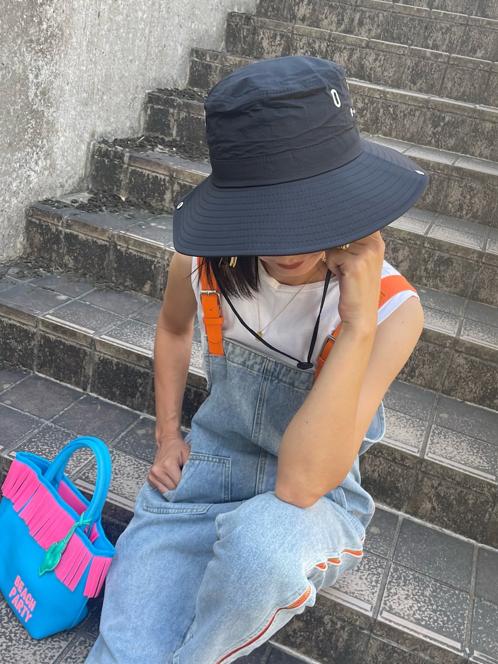 ブルー系のサロペット/オーバーオール、ホワイト系のTシャツ/カットソー、ブラック系のサンダルを着用したレディースの夏コーディネートの3枚目の写真