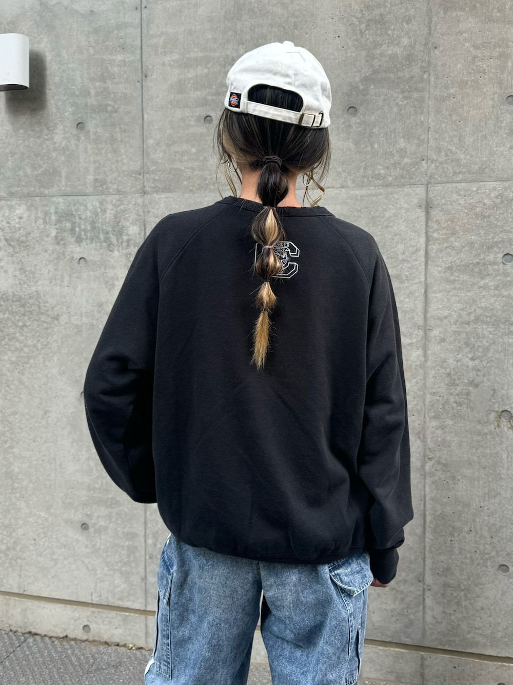 ブラック系のスウェット、ブルー系のデニムパンツ、ホワイト系のスニーカーを着用したレディースの冬コーディネートの5枚目の写真