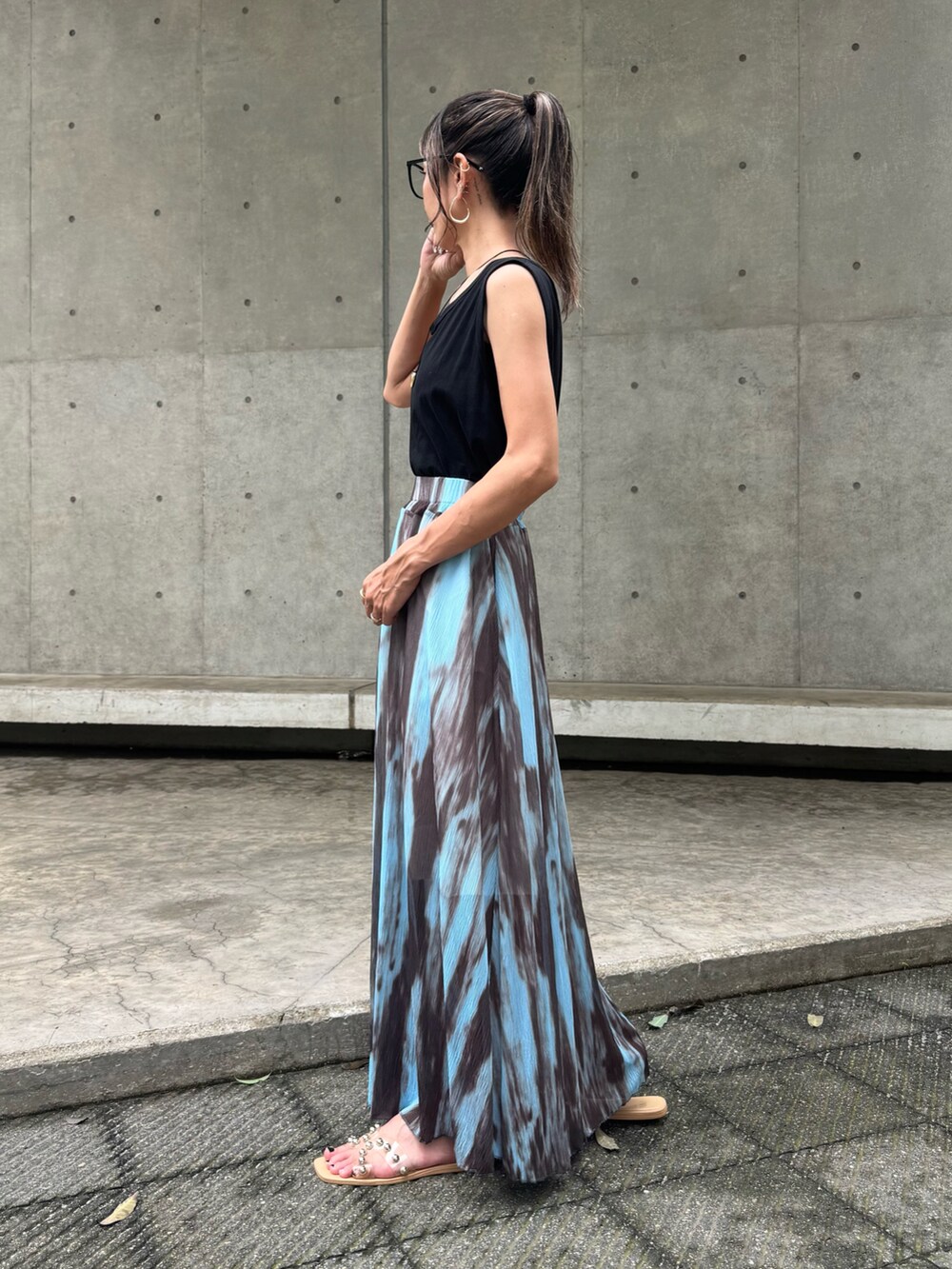 ブラック系のタンクトップ、ブルー系のスカート、ベージュ系のサンダルを着用したレディースの夏コーディネートの2枚目の写真