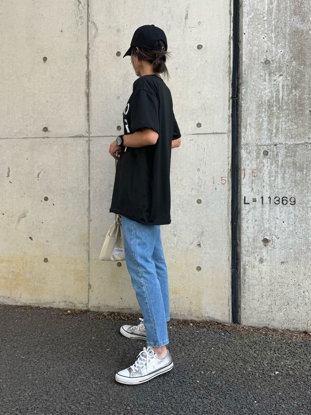 ブラック系のTシャツ/カットソー、ブルー系のデニムパンツ、ホワイト系のショルダーバッグを着用したレディースの春コーディネートの2枚目の写真