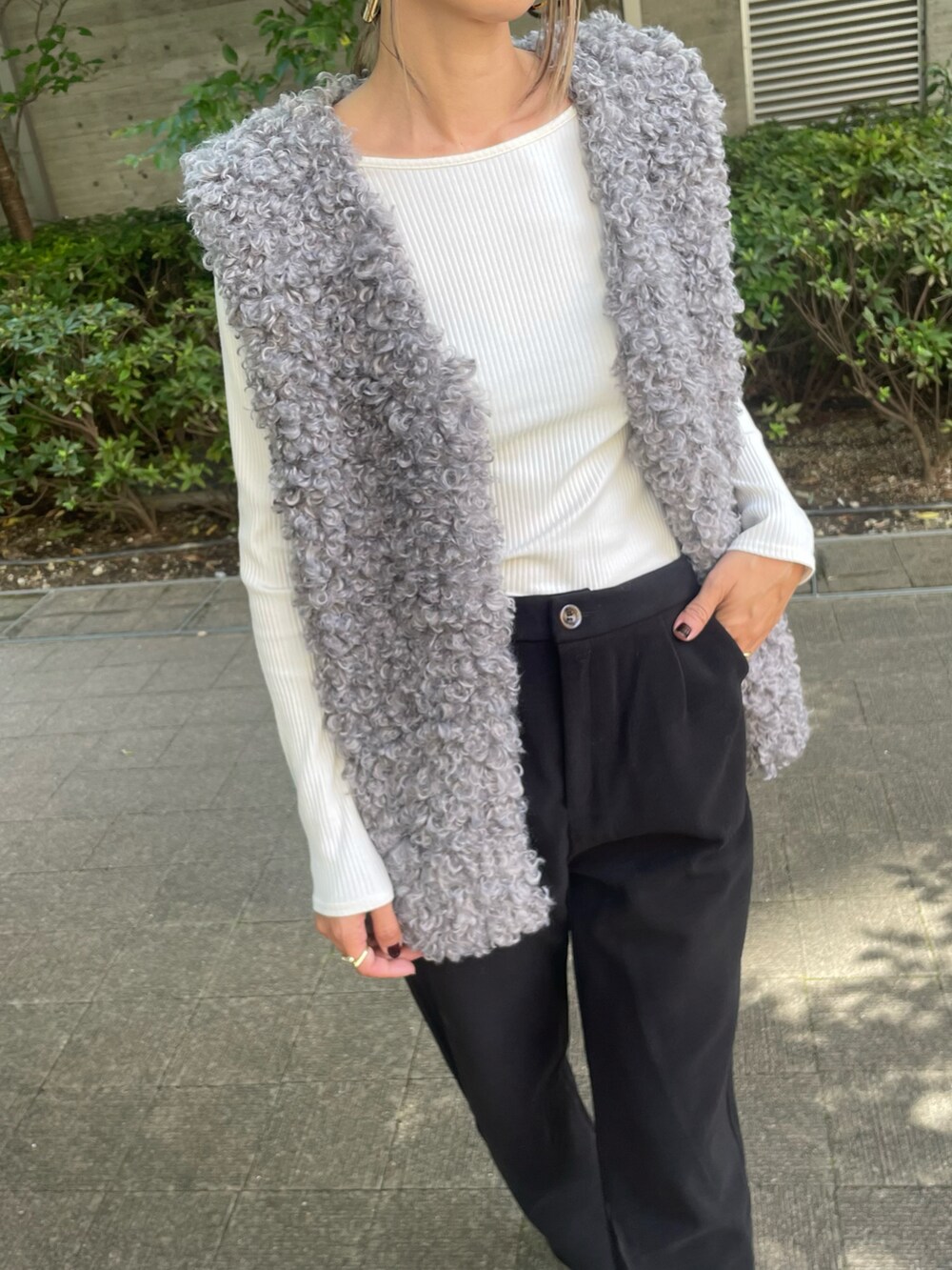 グレー系のベスト、ホワイト系のTシャツ/カットソー、ブラック系のその他パンツを着用したレディースの秋コーディネートの4枚目の写真