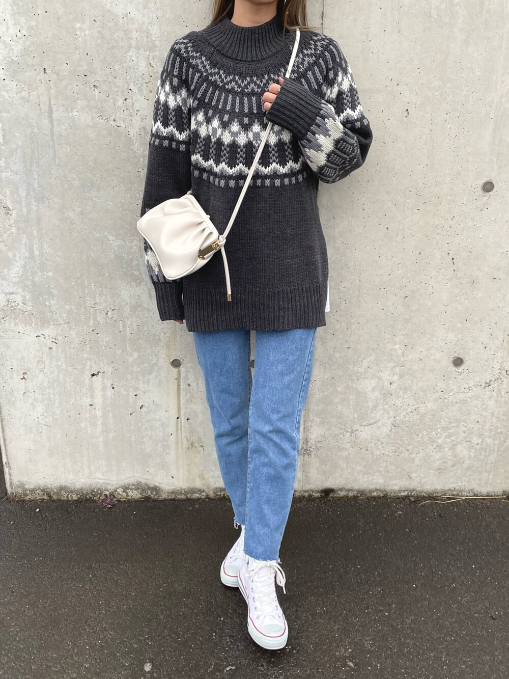 グレー系のニット/セーター、ブルー系のデニムパンツ、ホワイト系のショルダーバッグを着用したレディースの冬コーディネートの2枚目の写真