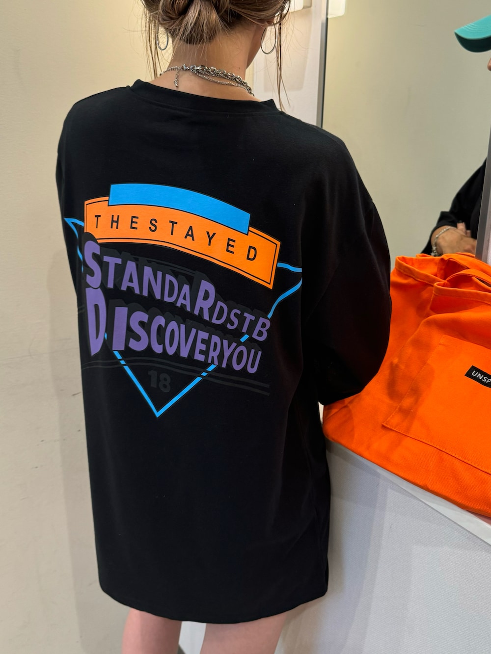 ブラック系のTシャツ/カットソー、オレンジ系のトートバッグ、ブラック系のスニーカーを着用したレディースの夏コーディネートの4枚目の写真