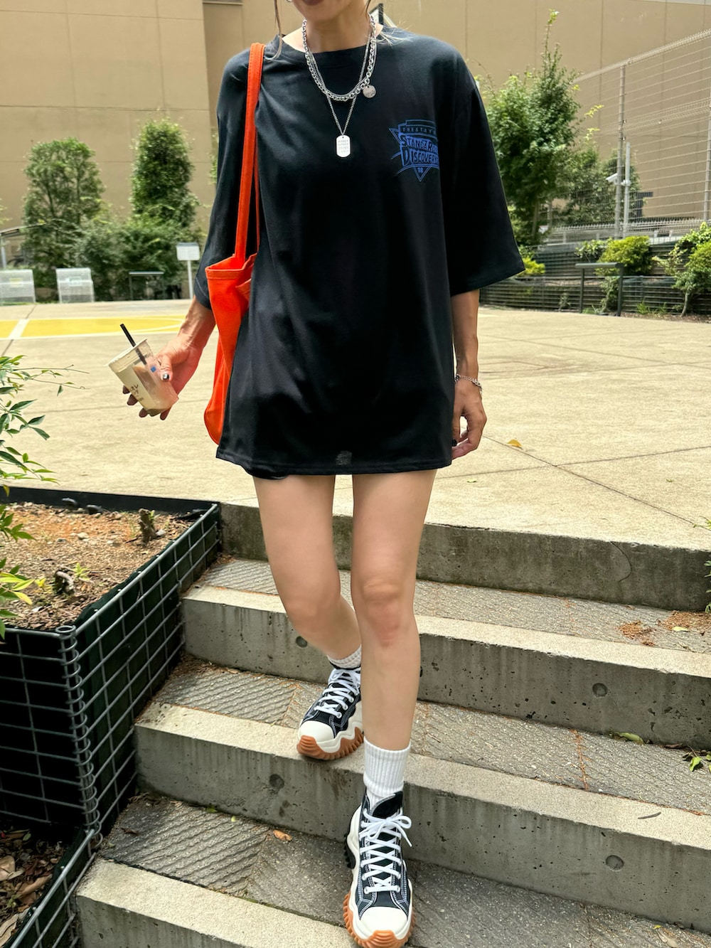 ブラック系のTシャツ/カットソー、オレンジ系のトートバッグ、ブラック系のスニーカーを着用したレディースの夏コーディネートの2枚目の写真