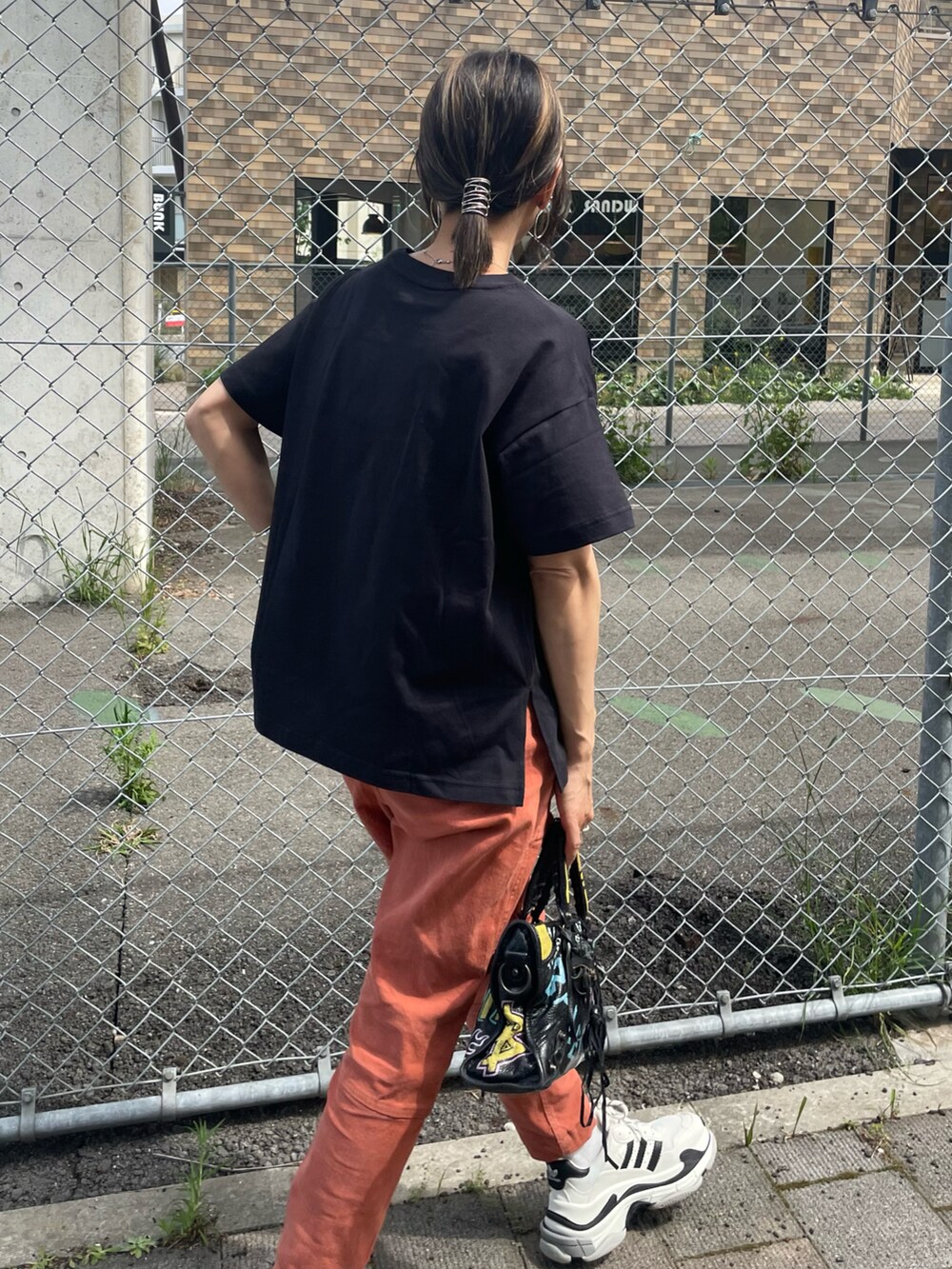 ブラック系のTシャツ/カットソー、レッド系のその他パンツ、ブラック系のバッグを着用したレディースの春コーディネートの3枚目の写真