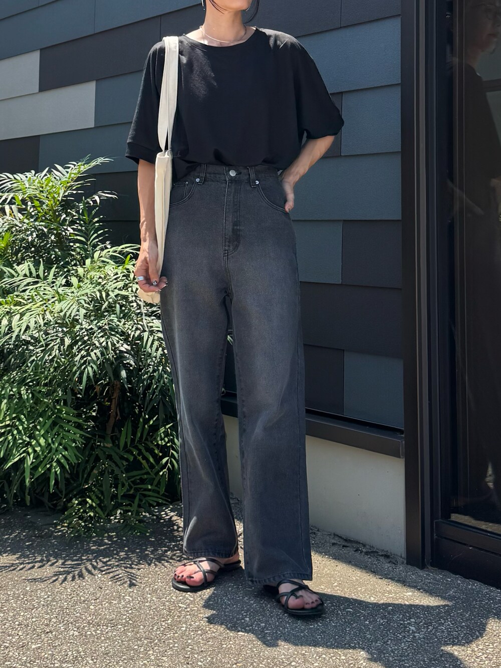 ブラック系のTシャツ/カットソー、ブラック系のデニムパンツ、ホワイト系のトートバッグを着用したレディースの夏コーディネートの2枚目の写真