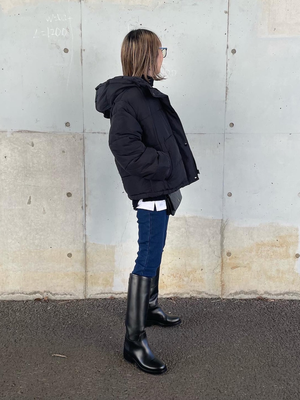 ブラック系のニット/セーター、ブルー系のデニムパンツ、ブラック系のダウンジャケット/コートを着用したレディースの秋コーディネートの3枚目の写真