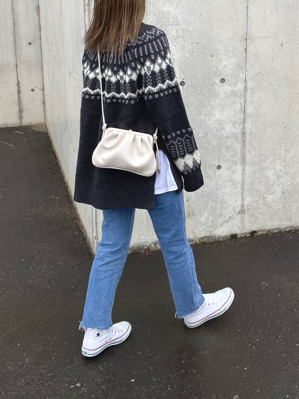 グレー系のニット/セーター、ブルー系のデニムパンツ、ホワイト系のショルダーバッグを着用したレディースの冬コーディネートの3枚目の写真