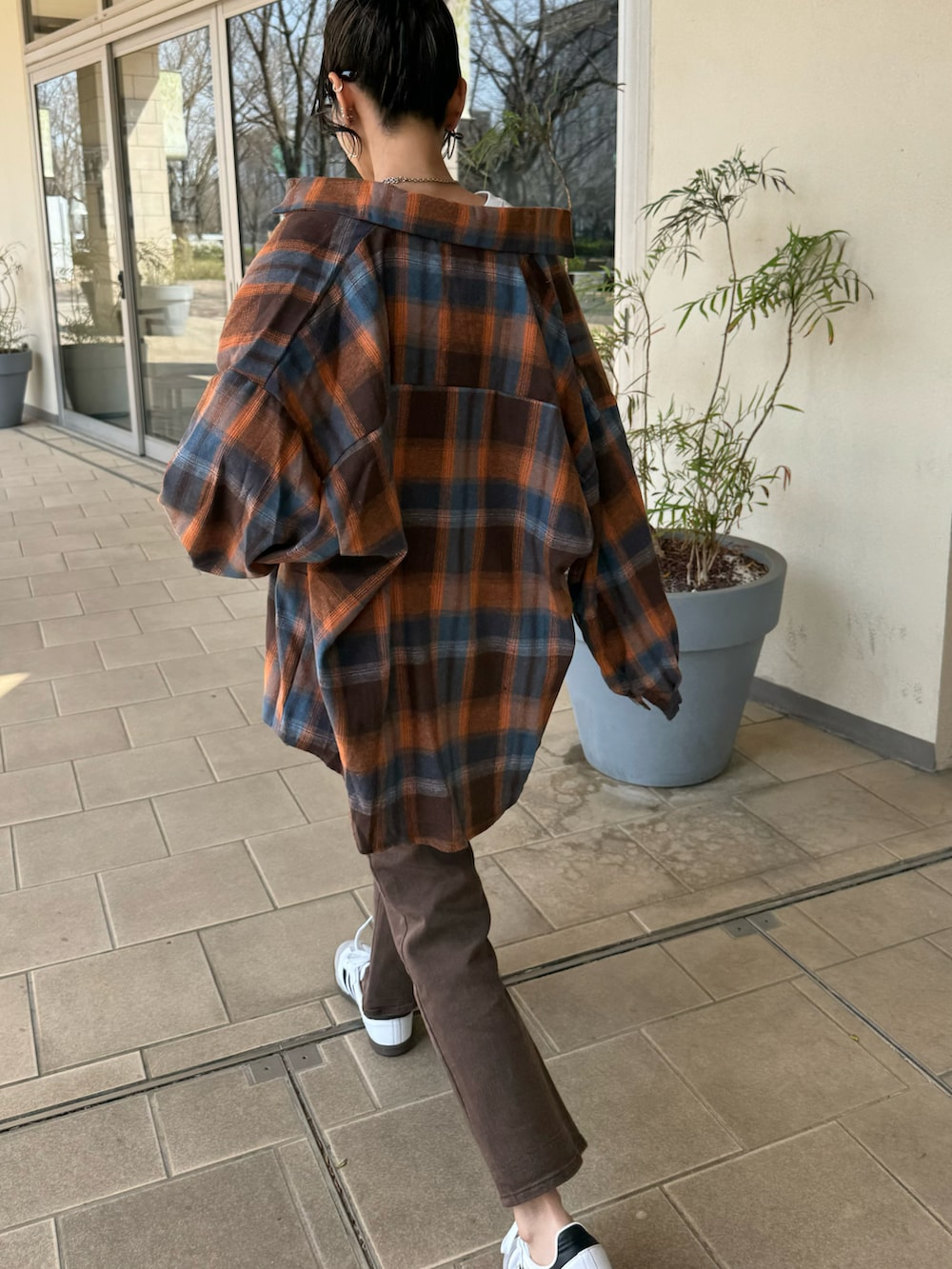 ブラウン系のシャツ/ブラウス、ブラウン系のデニムパンツ、ホワイト系のスニーカーを着用したレディースの春コーディネートの5枚目の写真