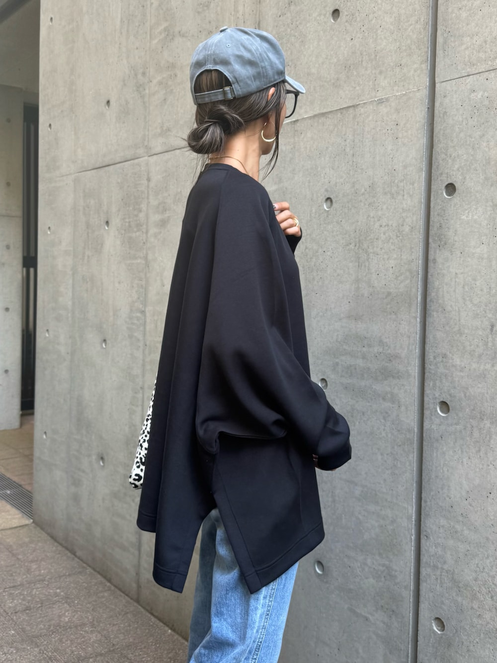 ブラック系のスウェット、ブルー系のデニムパンツ、ホワイト系のショルダーバッグを着用したレディースの秋コーディネートの5枚目の写真