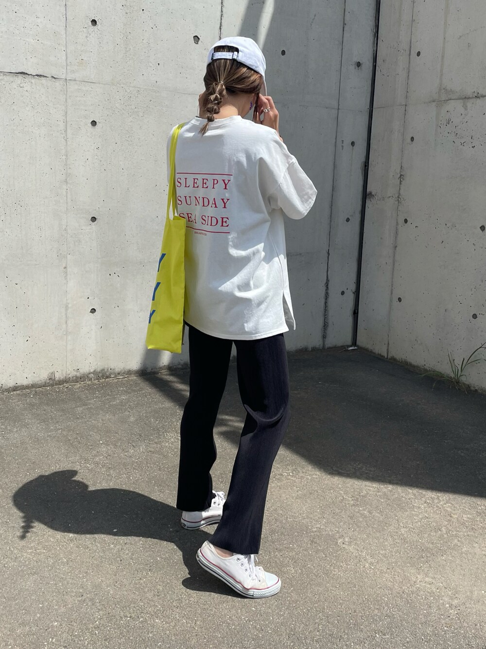 レッド系のTシャツ/カットソー、イエロー系のトートバッグ、ホワイト系のスニーカーを着用したレディースの春コーディネートの3枚目の写真