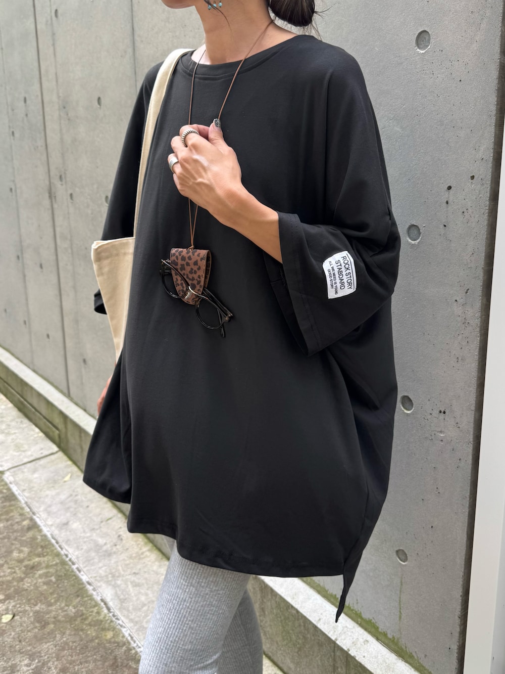 ブラック系のTシャツ/カットソー、ホワイト系のトートバッグ、ブラック系のスニーカーを着用したレディースの夏コーディネートの4枚目の写真