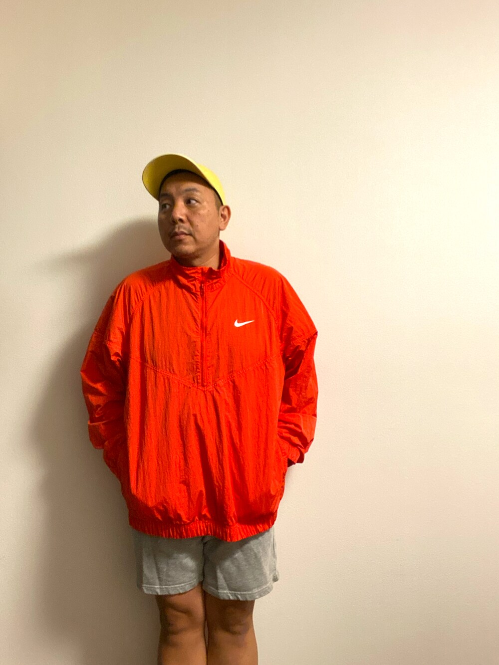 レッド系のナイロンジャケット、その他のスウェットパンツ、イエロー系のキャップを着用したメンズの秋コーディネートの2枚目の写真