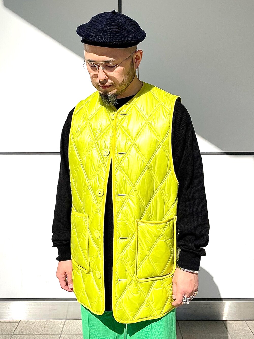 グリーン系のスウェットパンツ、ブラック系のローファー、イエロー系のベストを着用したメンズの秋コーディネートの3枚目の写真