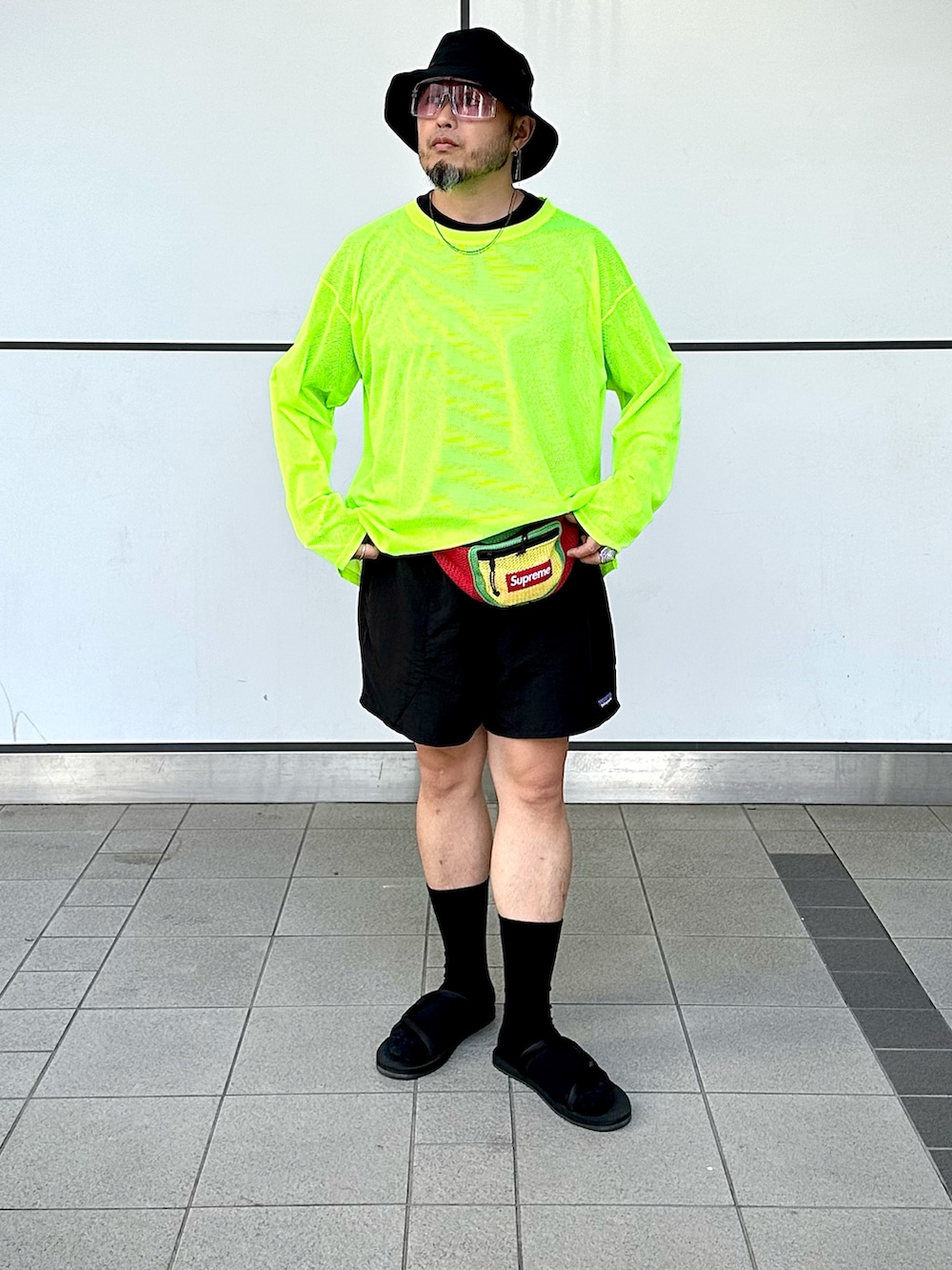 「夏コーデ、大人コーデ、カジュアルコーデ、ハーフパンツ、ショートパンツ、サングラス、バケットハット、レイヤードスタイル、ウエストポーチ、サンダル、サンダルに靴下、ネオンカラー、アウトドアスタイル、supreme、patagonia」｜「South2 West8のアイテム（Tシャツ/カットソー、イエロー系）」を使った、Yoshihito Hayashiさん（メンズ・170cm）の夏コーディネートの2枚目の写真