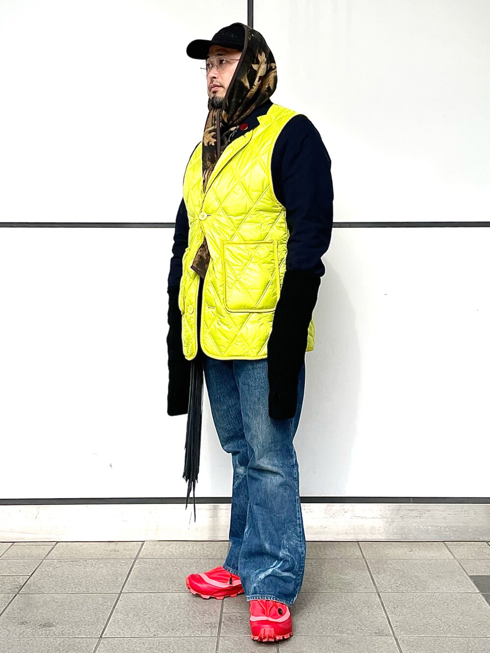 レッド系のスニーカー、ブルー系のデニムパンツ、イエロー系のベストを着用したメンズの冬コーディネートの5枚目の写真