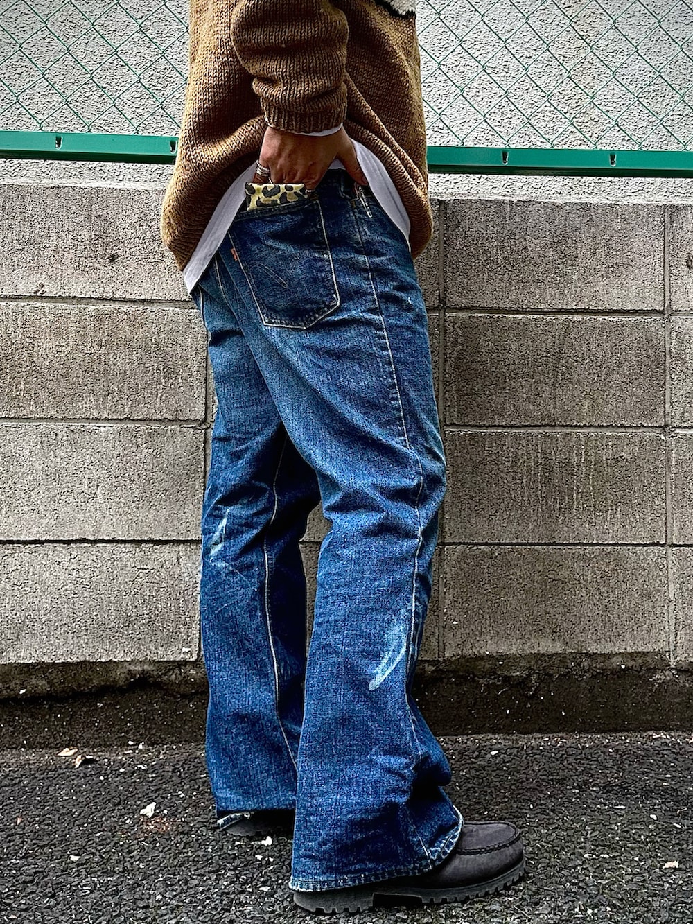 ブルー系のデニムパンツ、グレー系のモカシン/デッキシューズ、ベージュ系のニット/セーターを着用したメンズの秋コーディネートの4枚目の写真