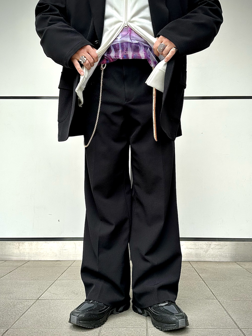 ブラック系のスラックス、ブラック系のテーラードジャケット、ホワイト系のジャージを着用したメンズの春コーディネートの5枚目の写真