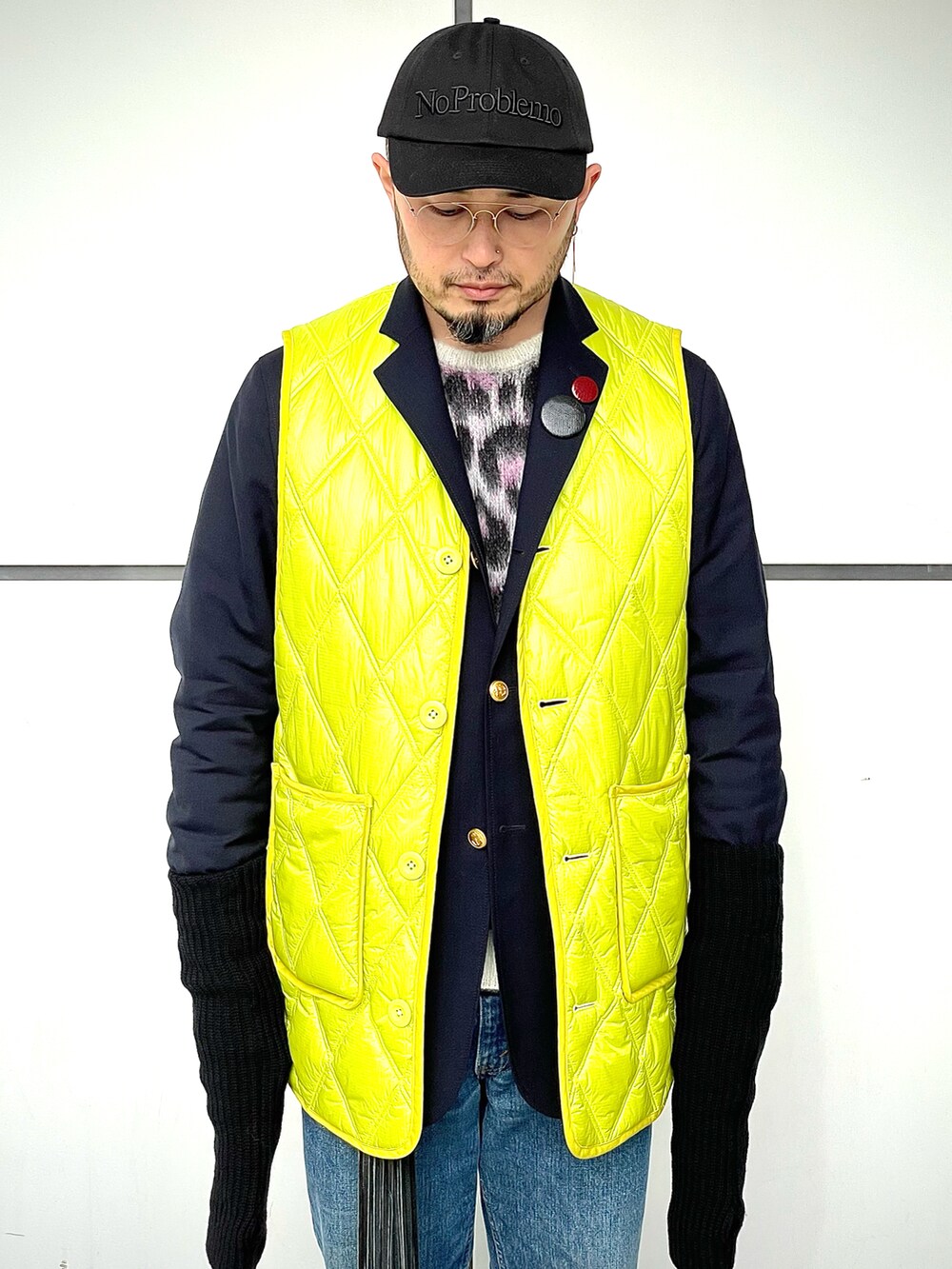 レッド系のスニーカー、ブルー系のデニムパンツ、イエロー系のベストを着用したメンズの冬コーディネートの3枚目の写真