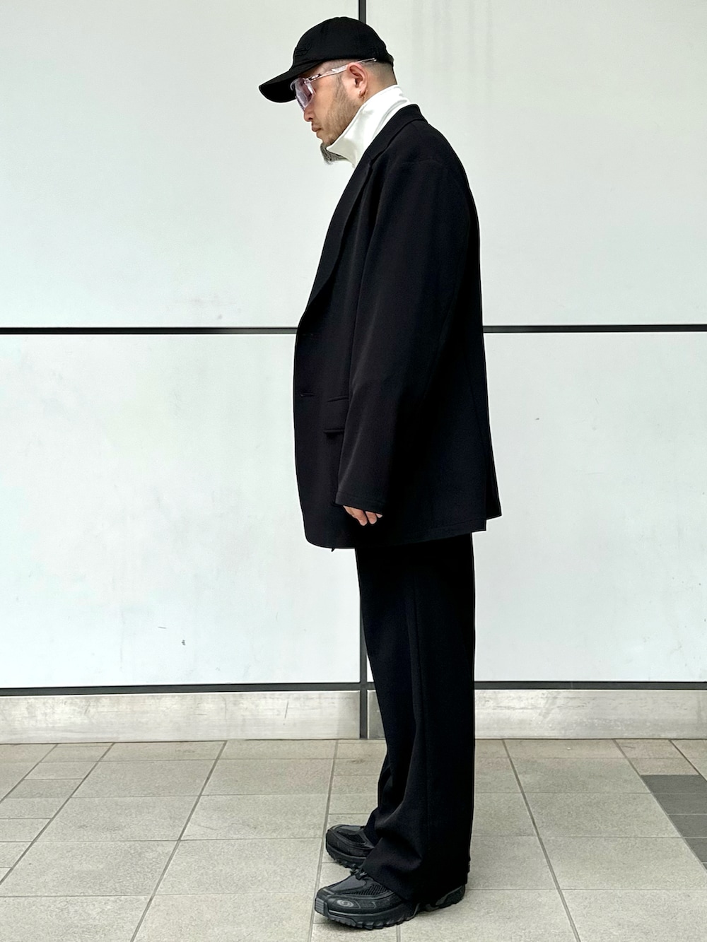 ブラック系のスラックス、ブラック系のテーラードジャケット、ホワイト系のジャージを着用したメンズの春コーディネートの2枚目の写真