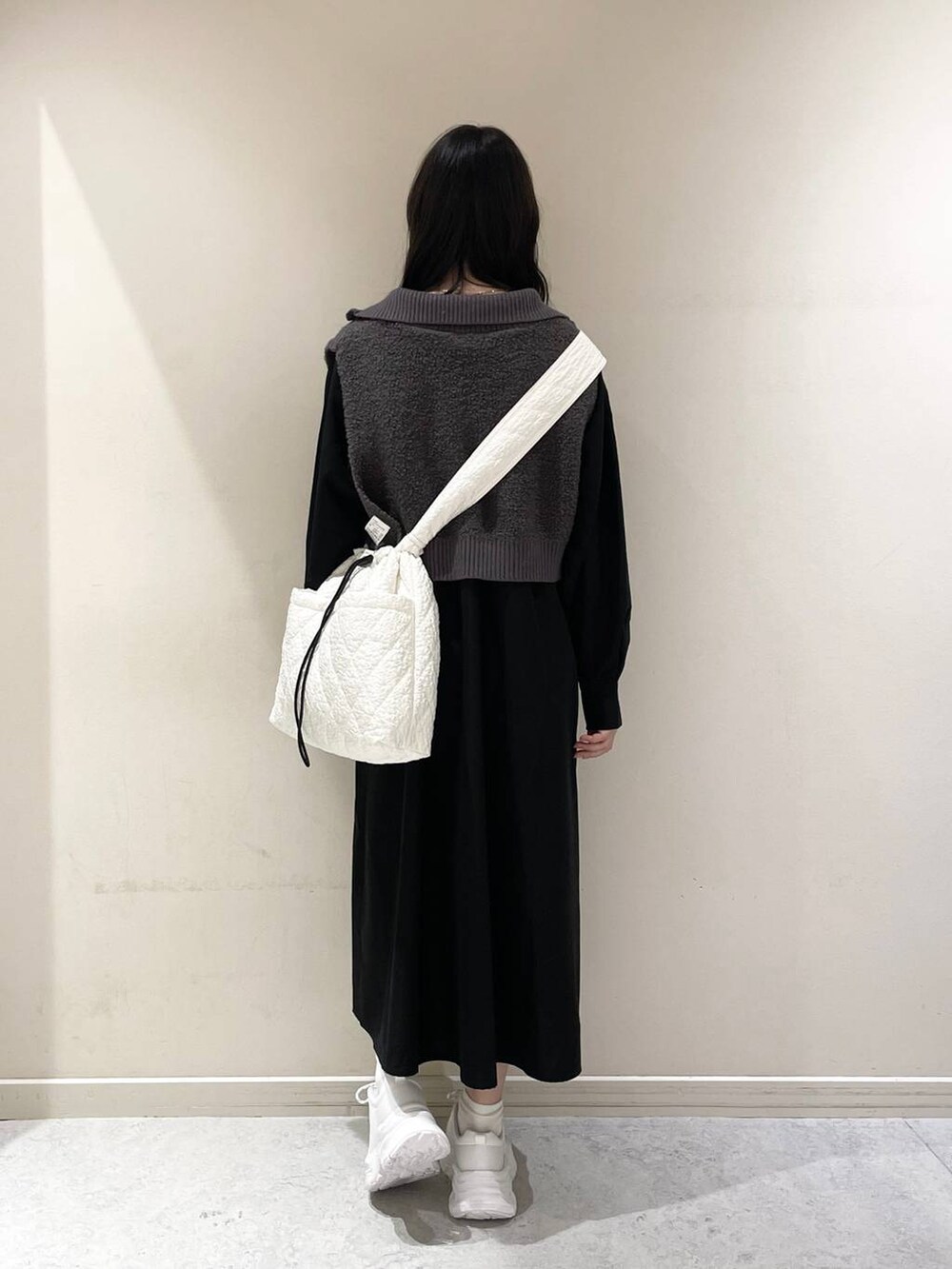 ホワイト系のショルダーバッグ、ホワイト系のスニーカー、グレー系のワンピースを着用したレディースの秋コーディネートの3枚目の写真