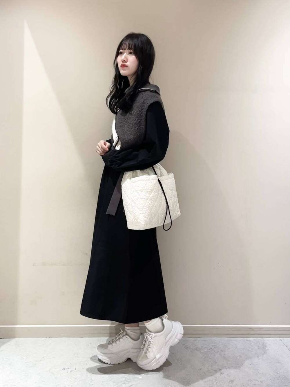 ホワイト系のショルダーバッグ、ホワイト系のスニーカー、グレー系のワンピースを着用したレディースの秋コーディネートの2枚目の写真