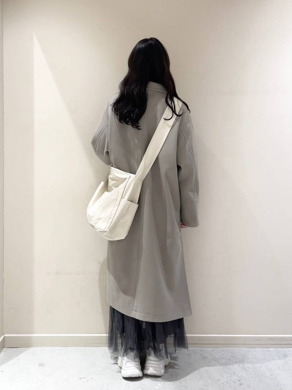 ホワイト系のボディバッグ/ウエストポーチ、ホワイト系のチェスターコート、ブルー系のTシャツ/カットソーを着用したレディースの冬コーディネートの3枚目の写真