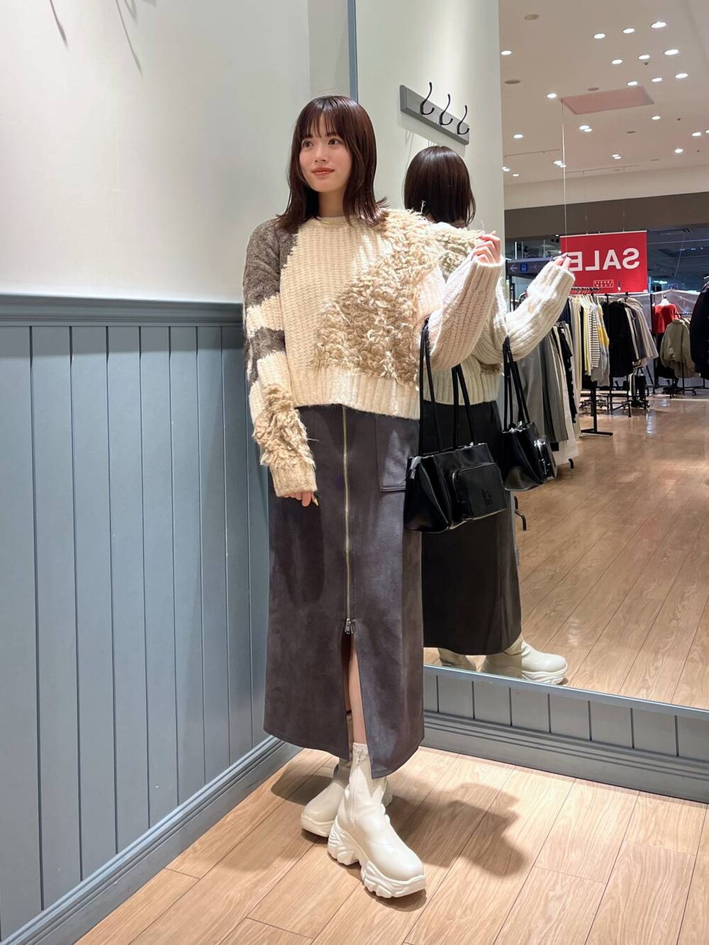 ホワイト系のブーツ、ブラック系のショルダーバッグ、グレー系のスカートを着用したレディースの冬コーディネートの3枚目の写真