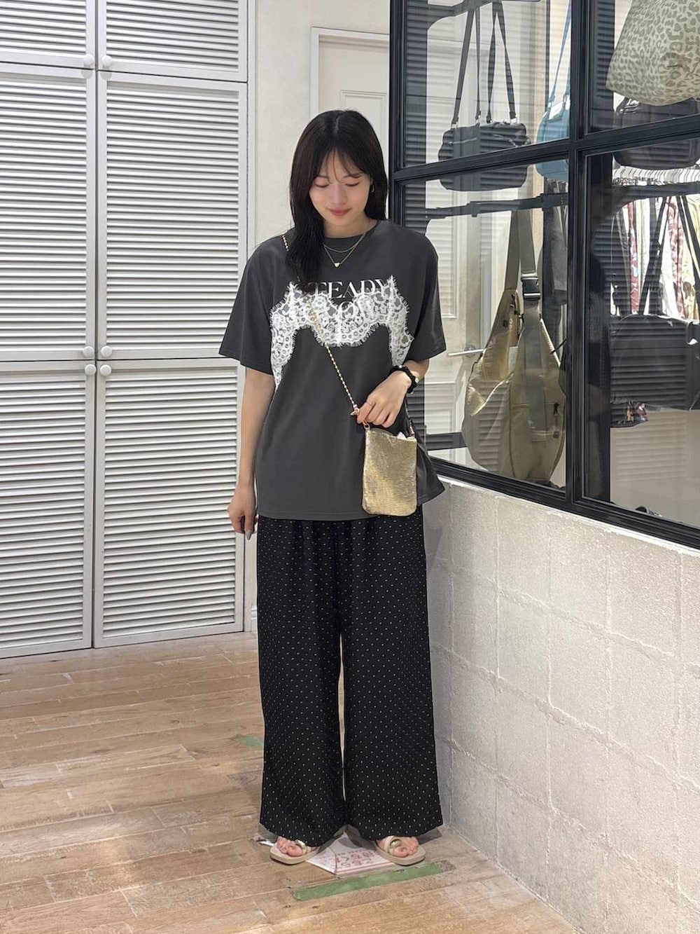 ゴールド系のショルダーバッグ、グレー系のTシャツ/カットソー、ホワイト系のサンダルを着用したレディースの夏コーディネートの3枚目の写真