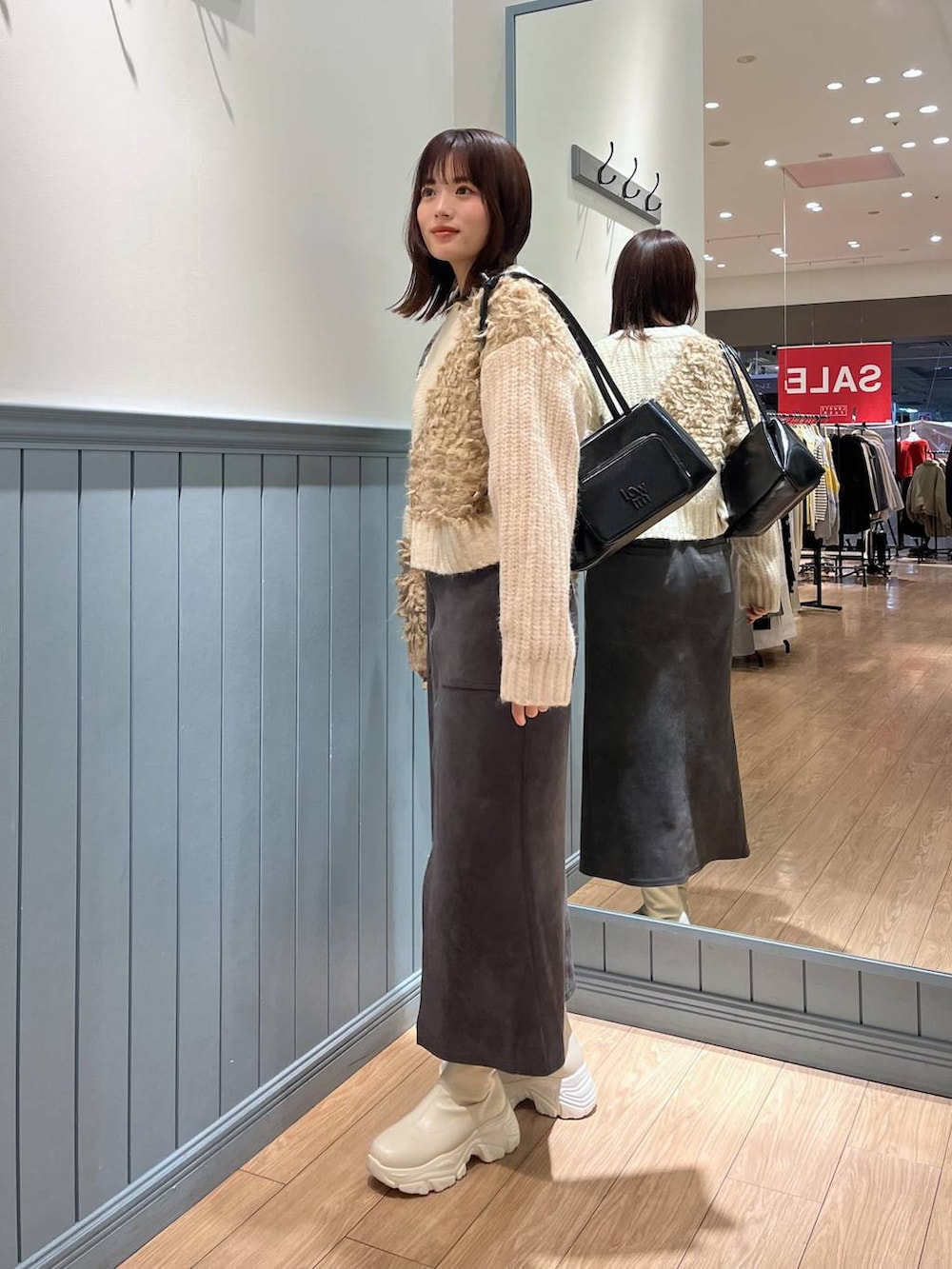 ホワイト系のブーツ、ブラック系のショルダーバッグ、グレー系のスカートを着用したレディースの冬コーディネートの4枚目の写真