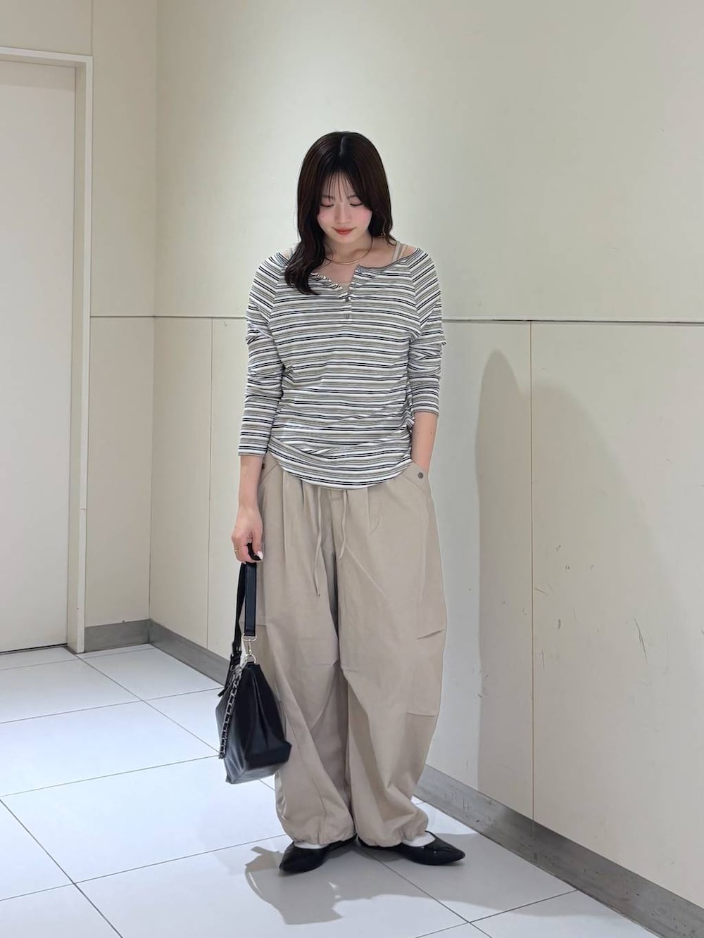 ホワイト系のTシャツ/カットソー、ブラック系のショルダーバッグ、ベージュ系のその他パンツを着用したレディースの春コーディネートの6枚目の写真